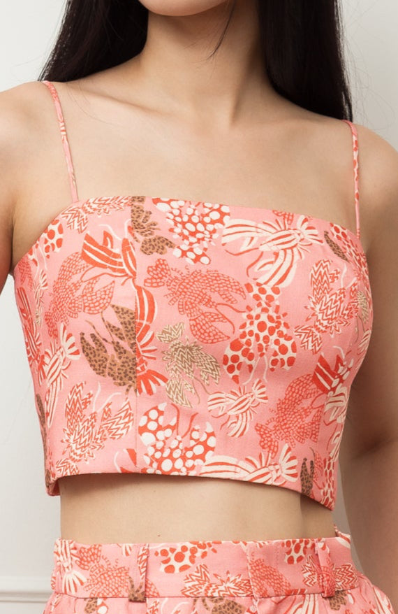Woman wearing a coral floral outfit against a white paneled wall