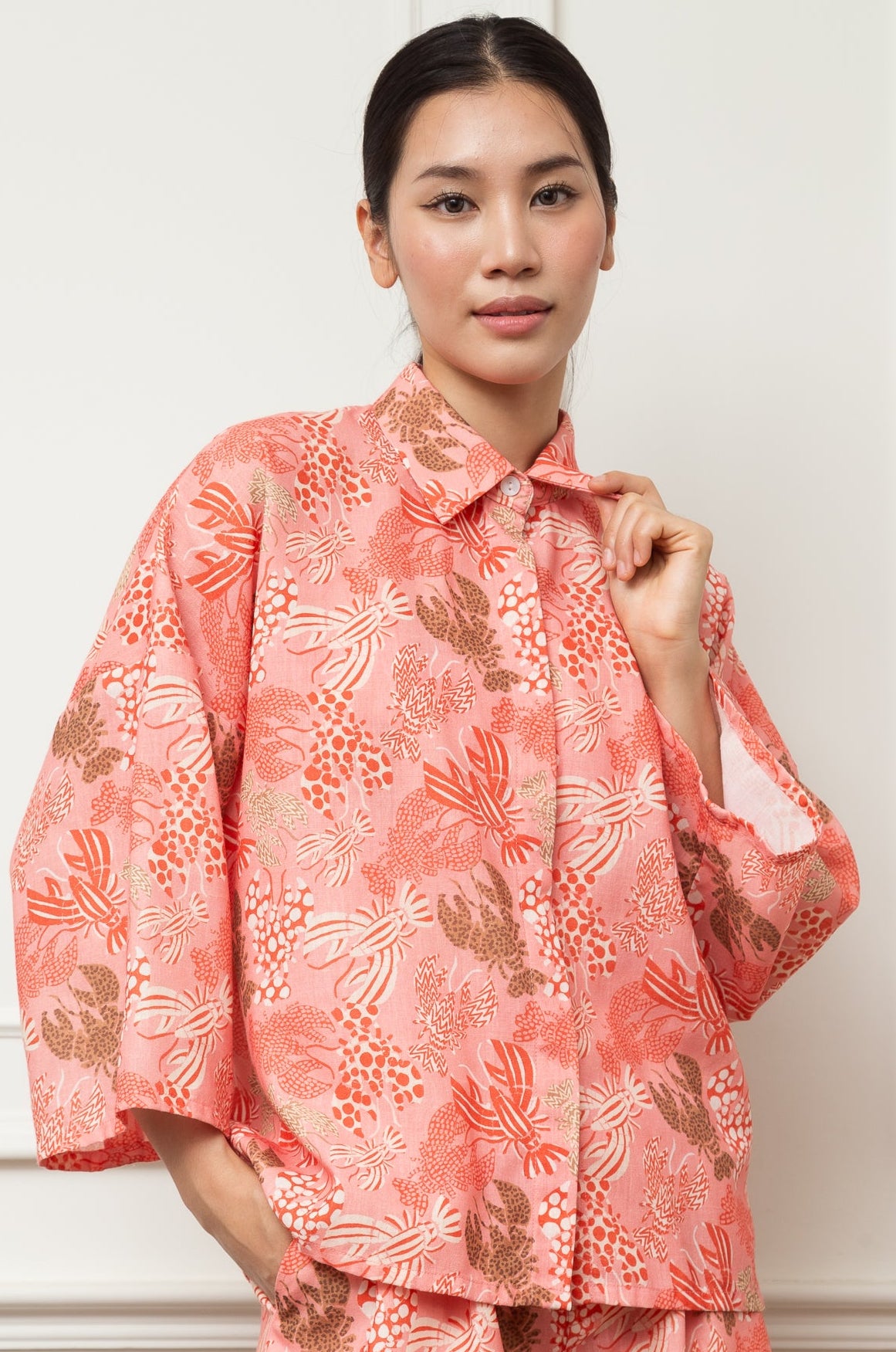 Woman wearing a pink floral outfit against a white background