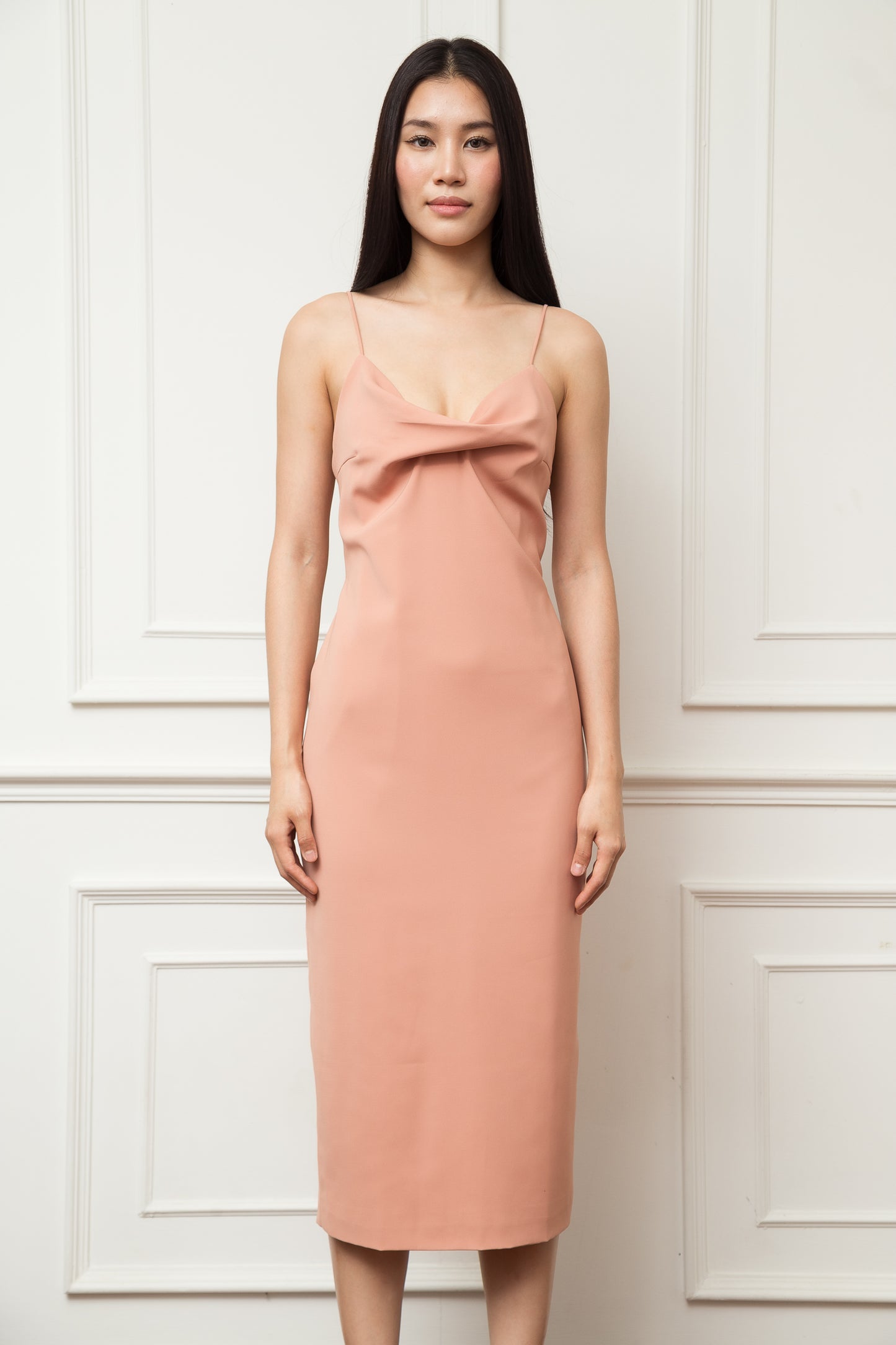Woman wearing a pink dress against a white paneled wall